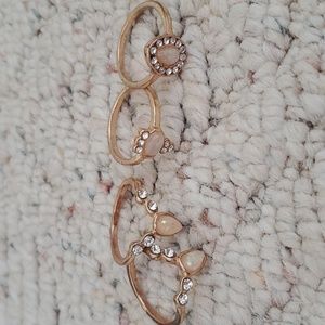 set of 4 gold rings with white and pink designs.